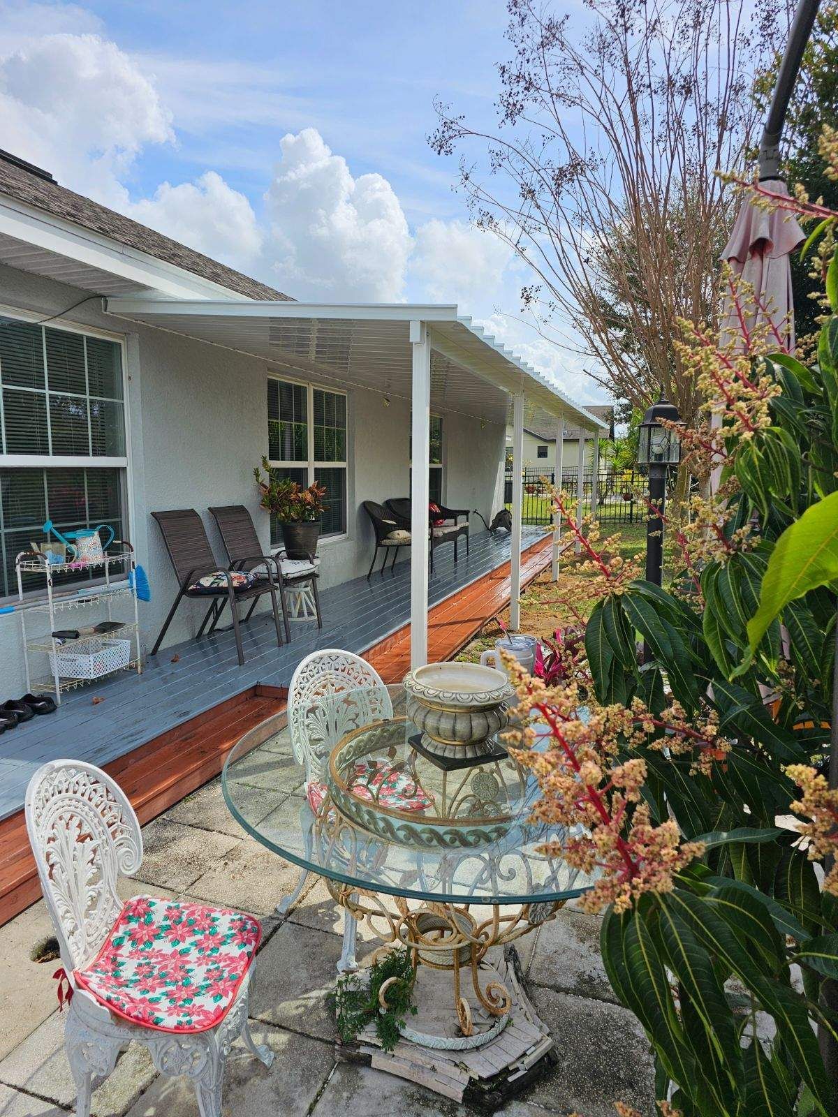 There is a table and chairs on the porch of a house.