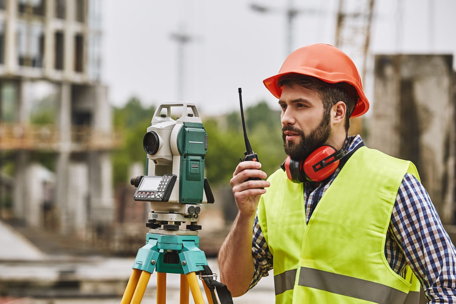 Precise measurements surveyor engineer in protective wear and red helmet using geodetic equipment