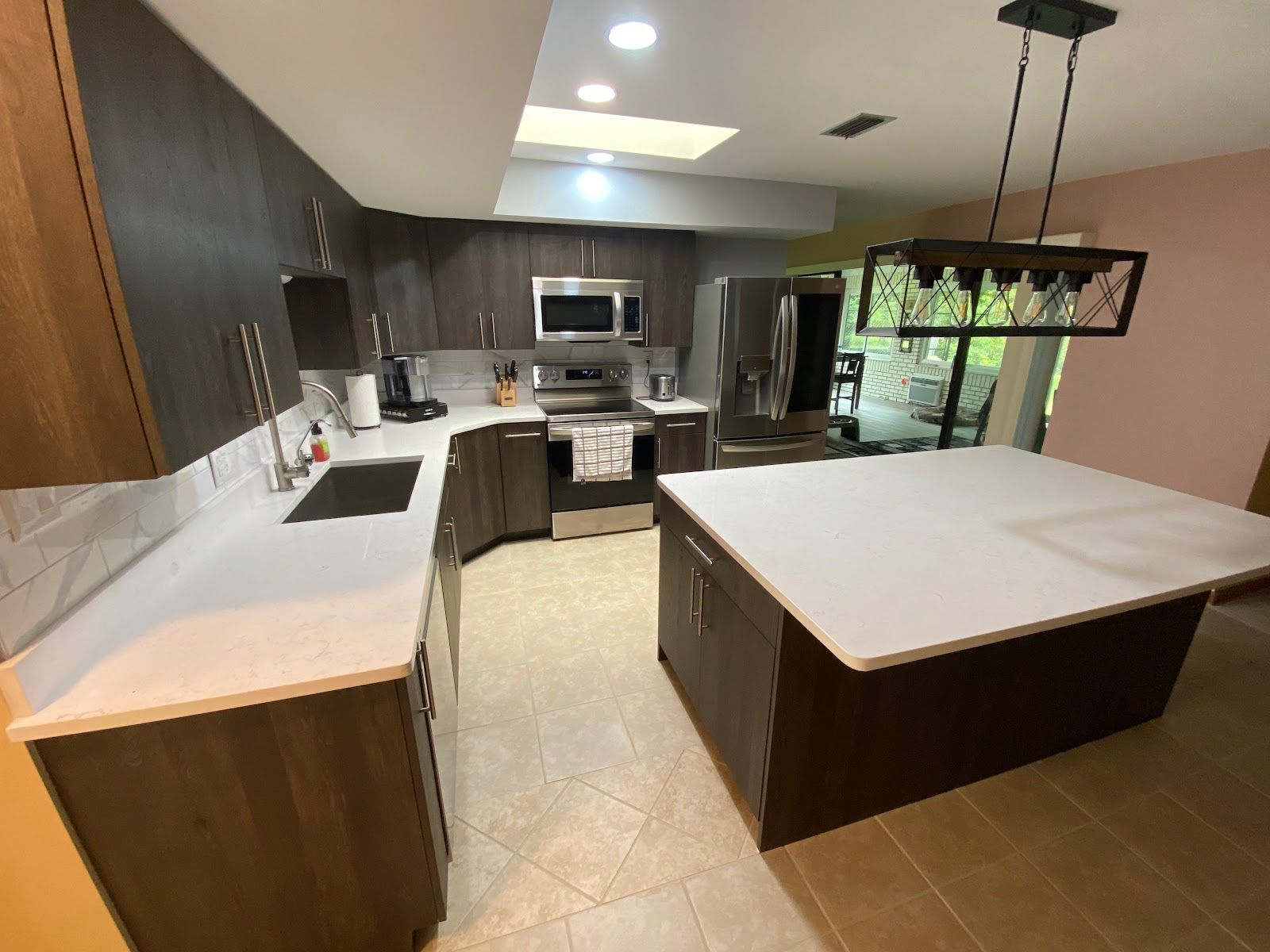 A kitchen with a large island in the middle and stainless steel appliances.