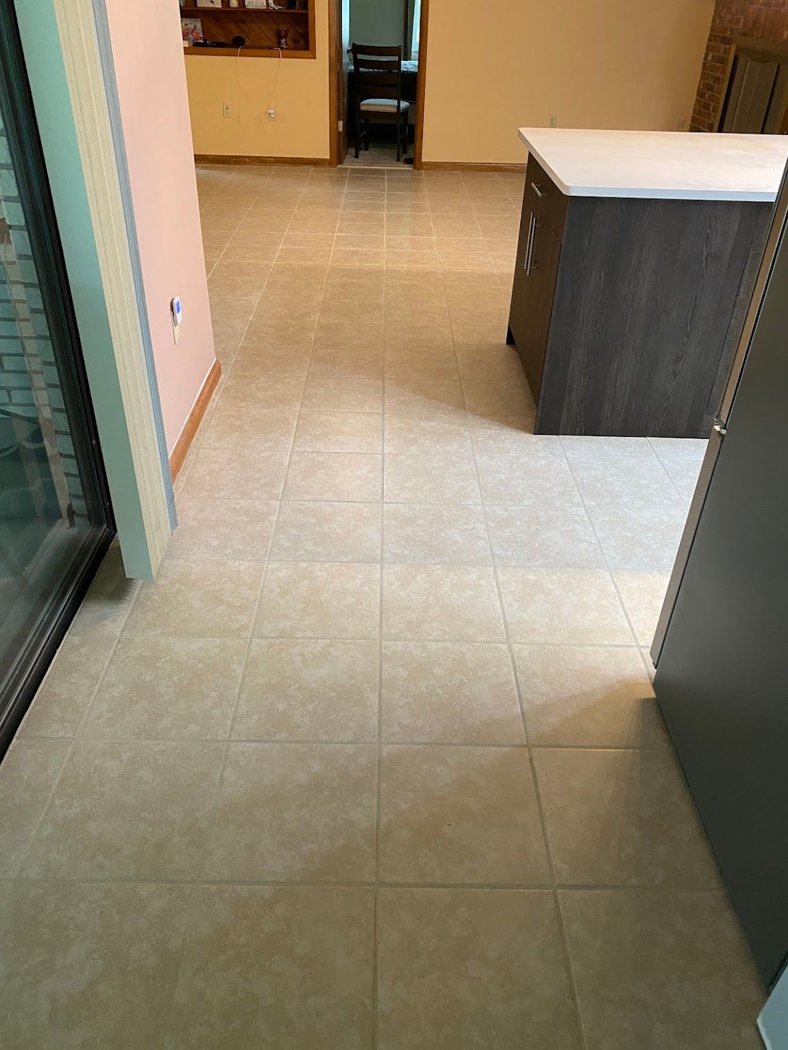 A tiled floor in a kitchen with a table and cabinets.