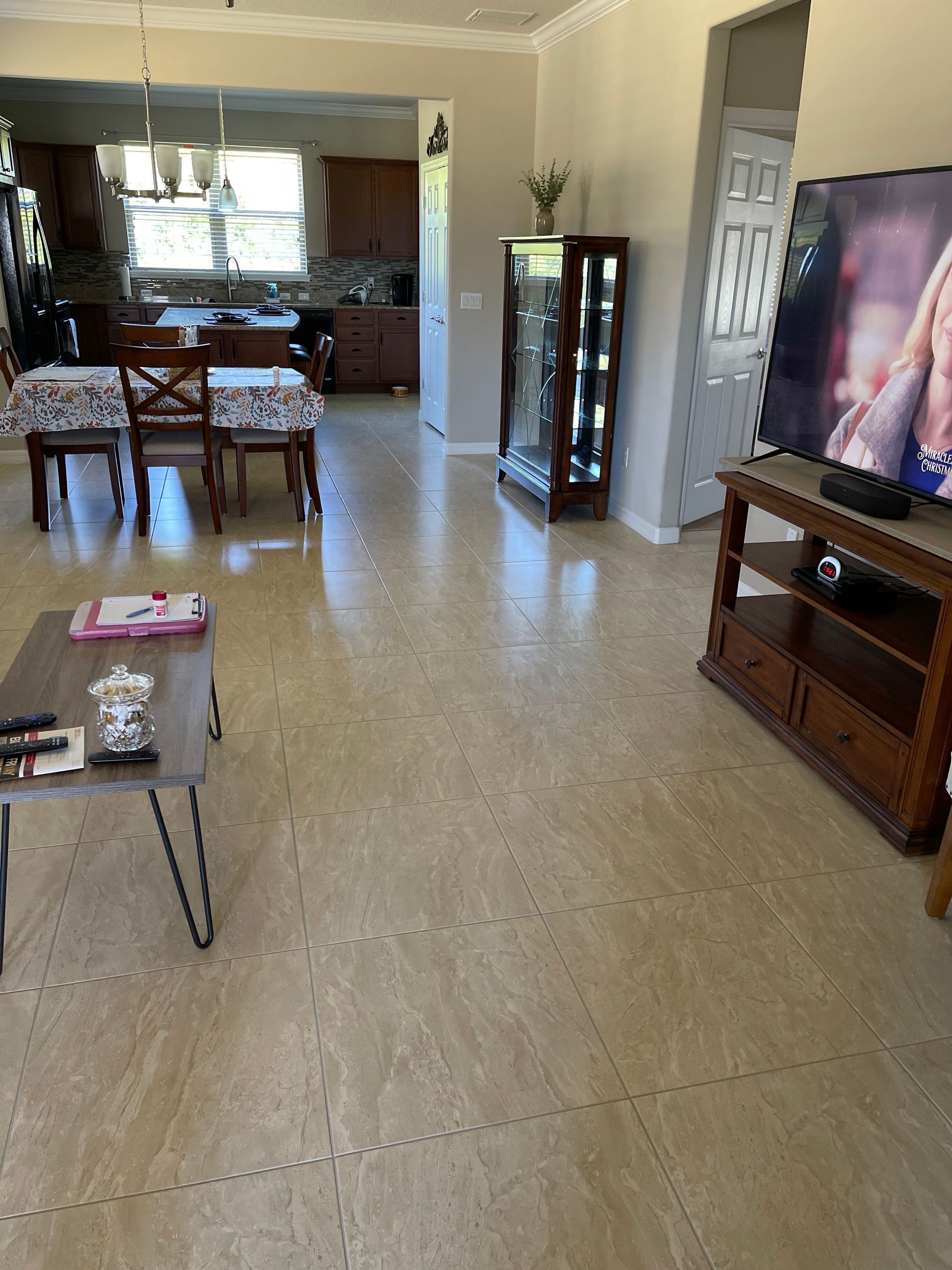 A person is plastering a tile floor with a spatula.