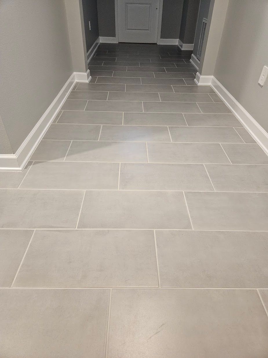 A shower stall with white tiles and a drain