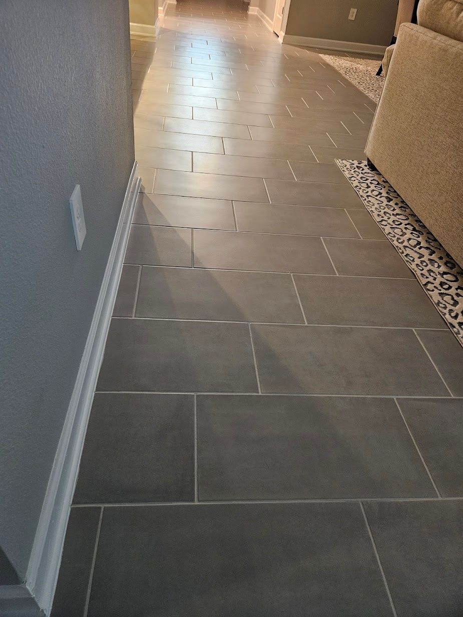 A hallway with tile floors and a couch in the background.