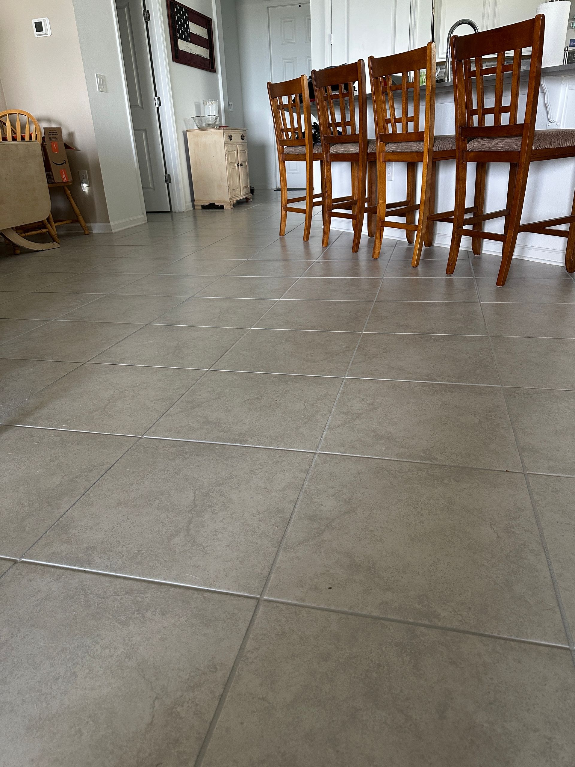 A person wearing black gloves is cleaning a tile floor with a sponge.