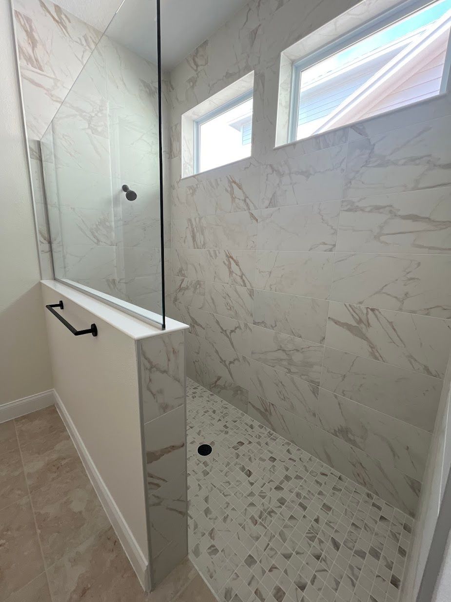 A bathroom with a walk in shower and marble walls.