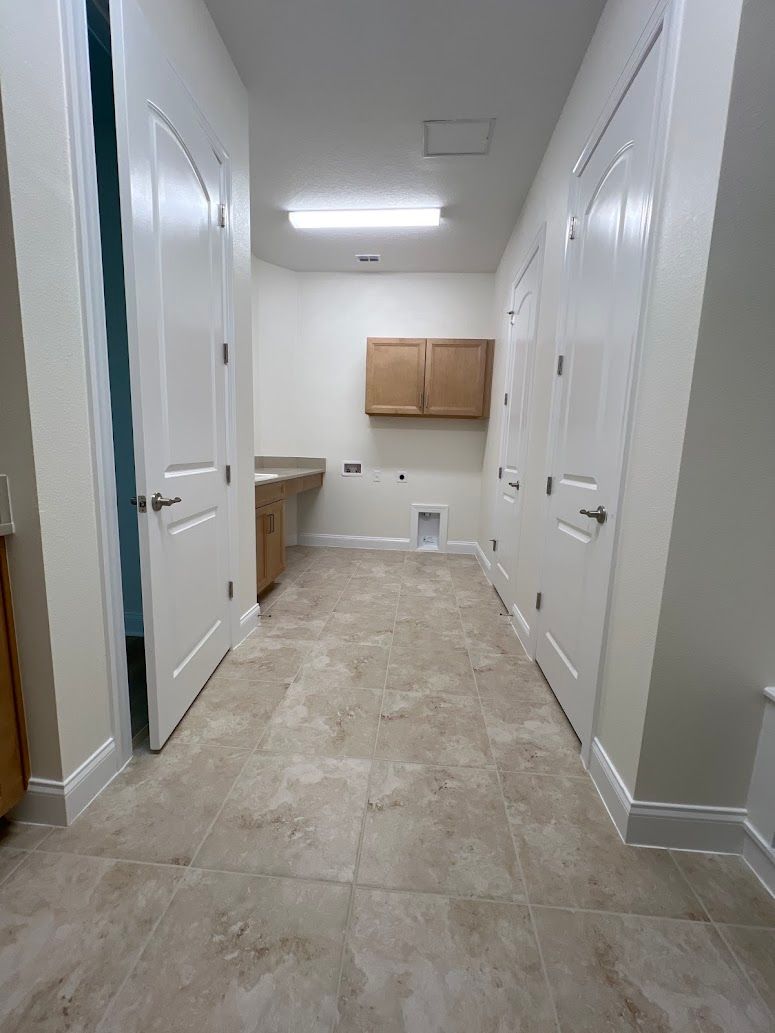 A hallway in a house with tile floors and white walls.