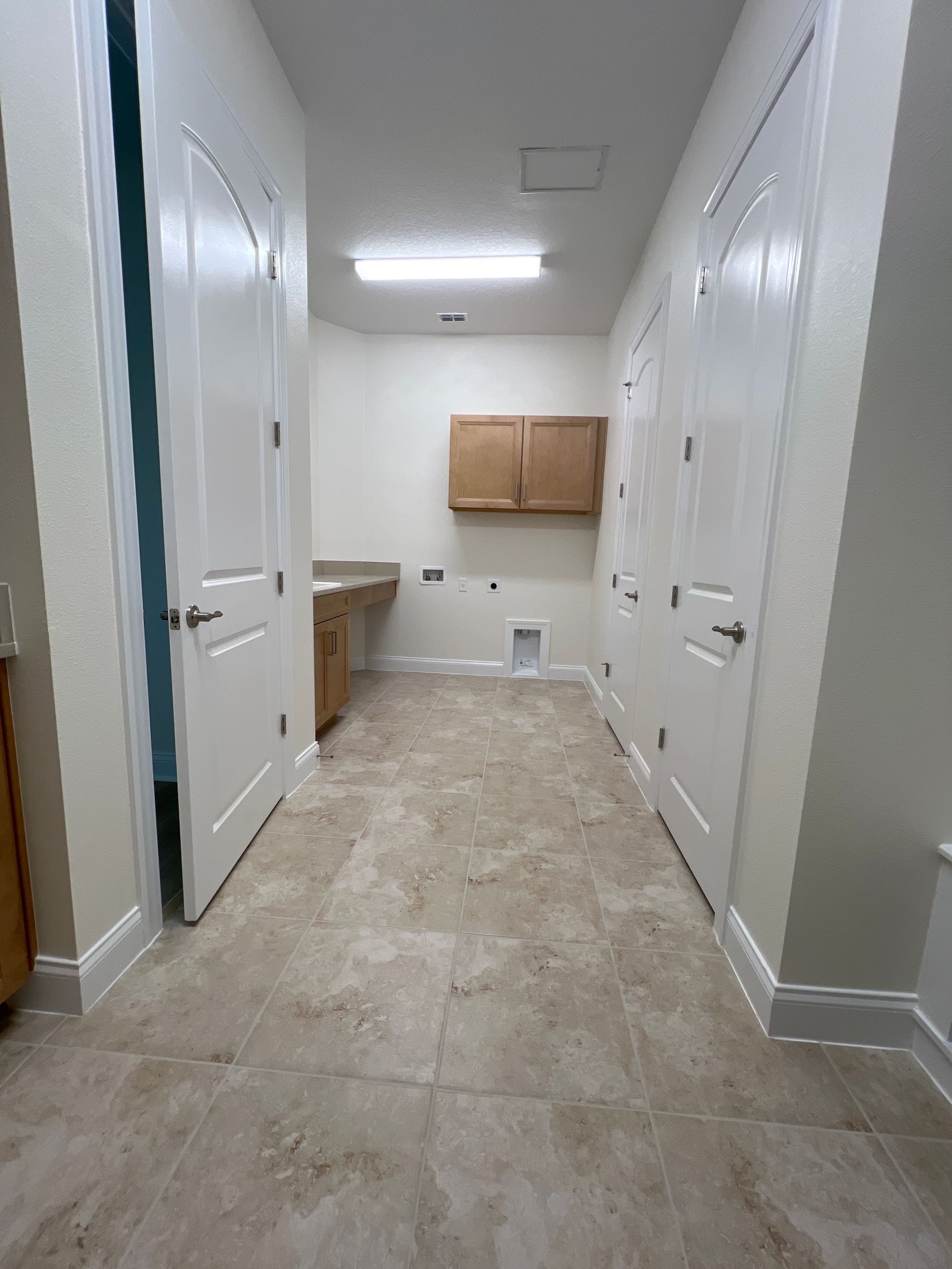 A hallway in a house with tile floors and white doors.
