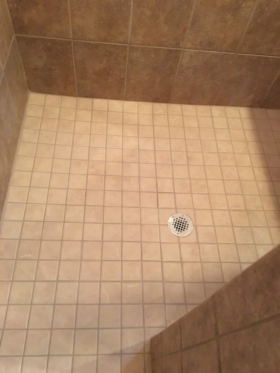 A bathroom with a tiled floor and a drain.