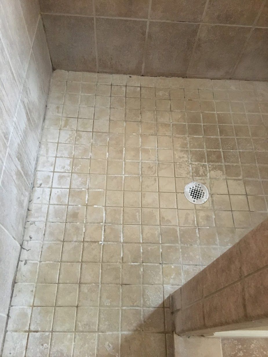 A bathroom with a tiled floor and a drain.
