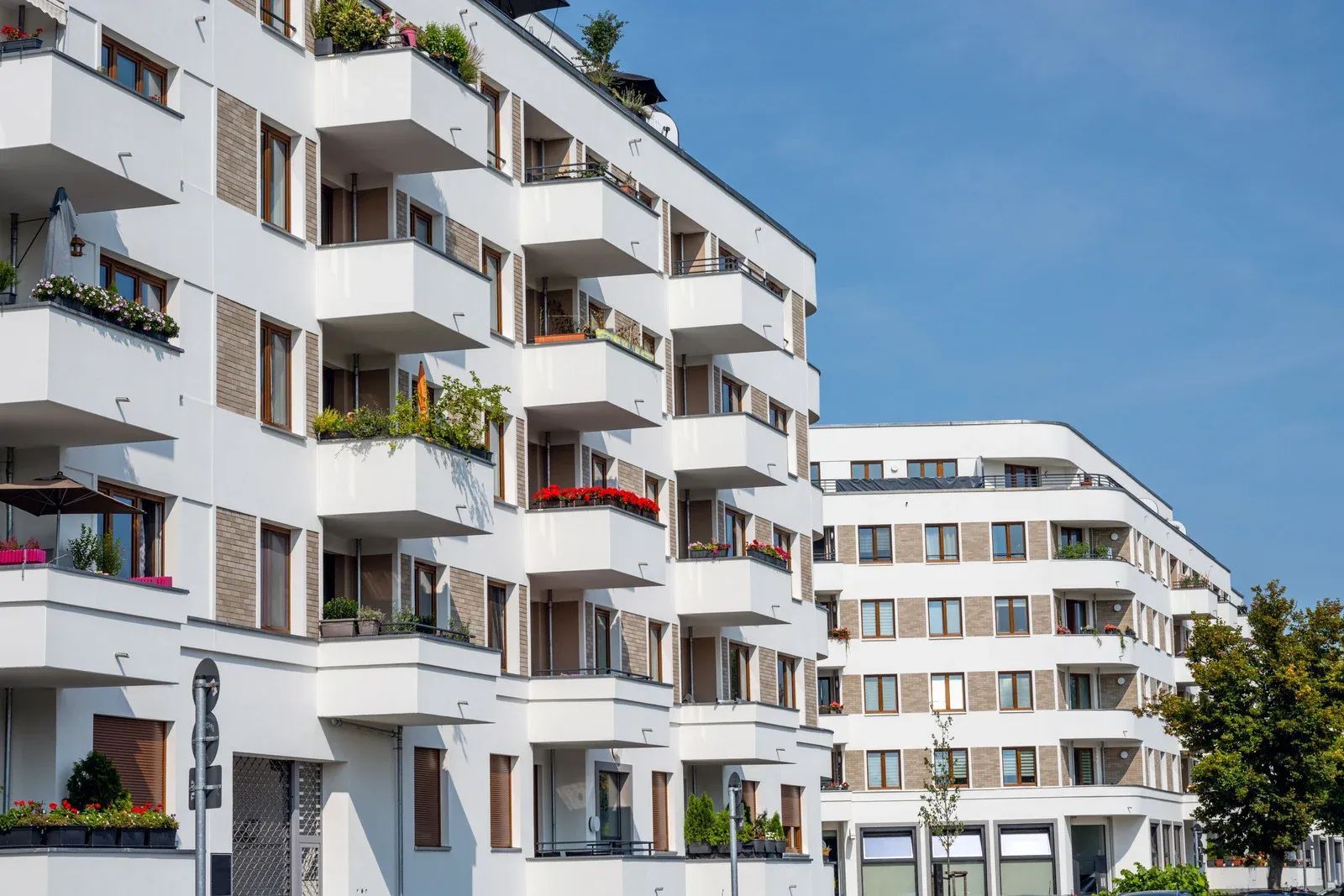 White apartment buildings with balconies, blue sky.