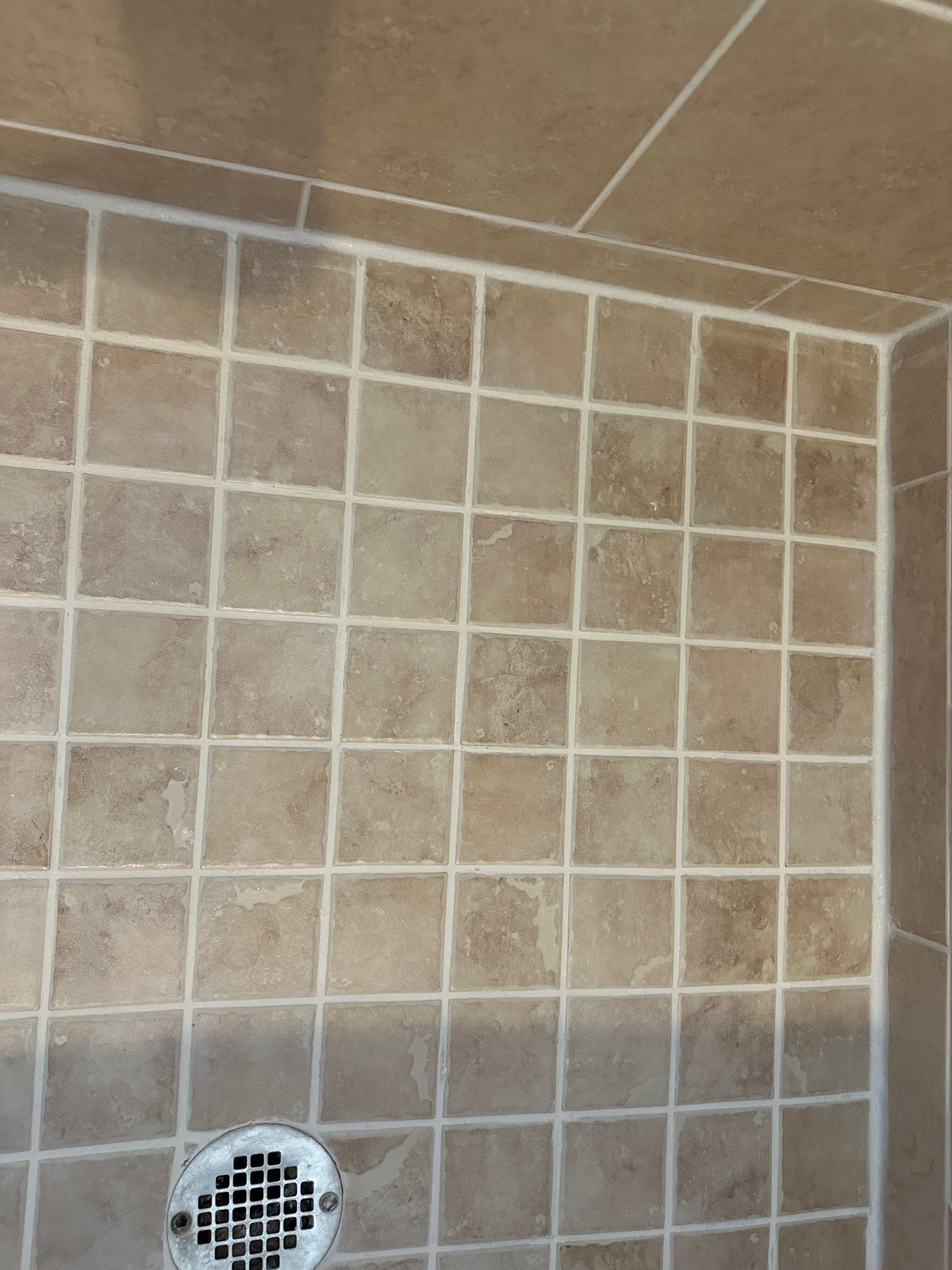 White tiled shower wall with gray grout.