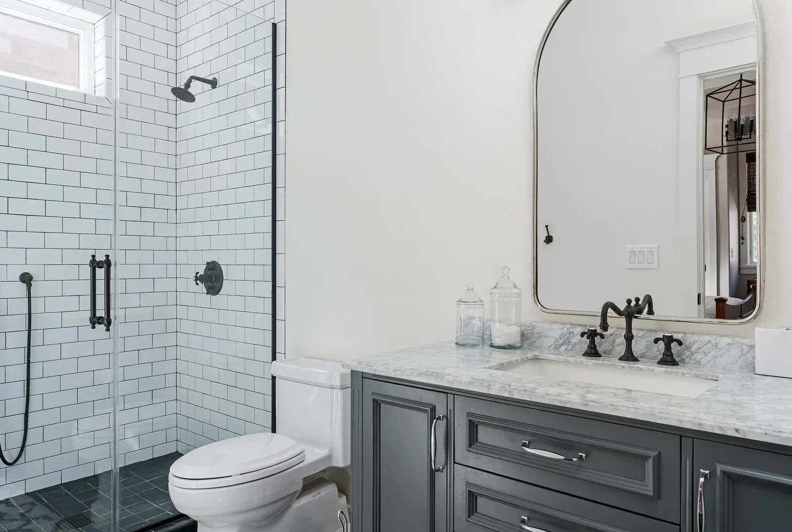 A bathroom with a toilet , sink , shower and mirror.