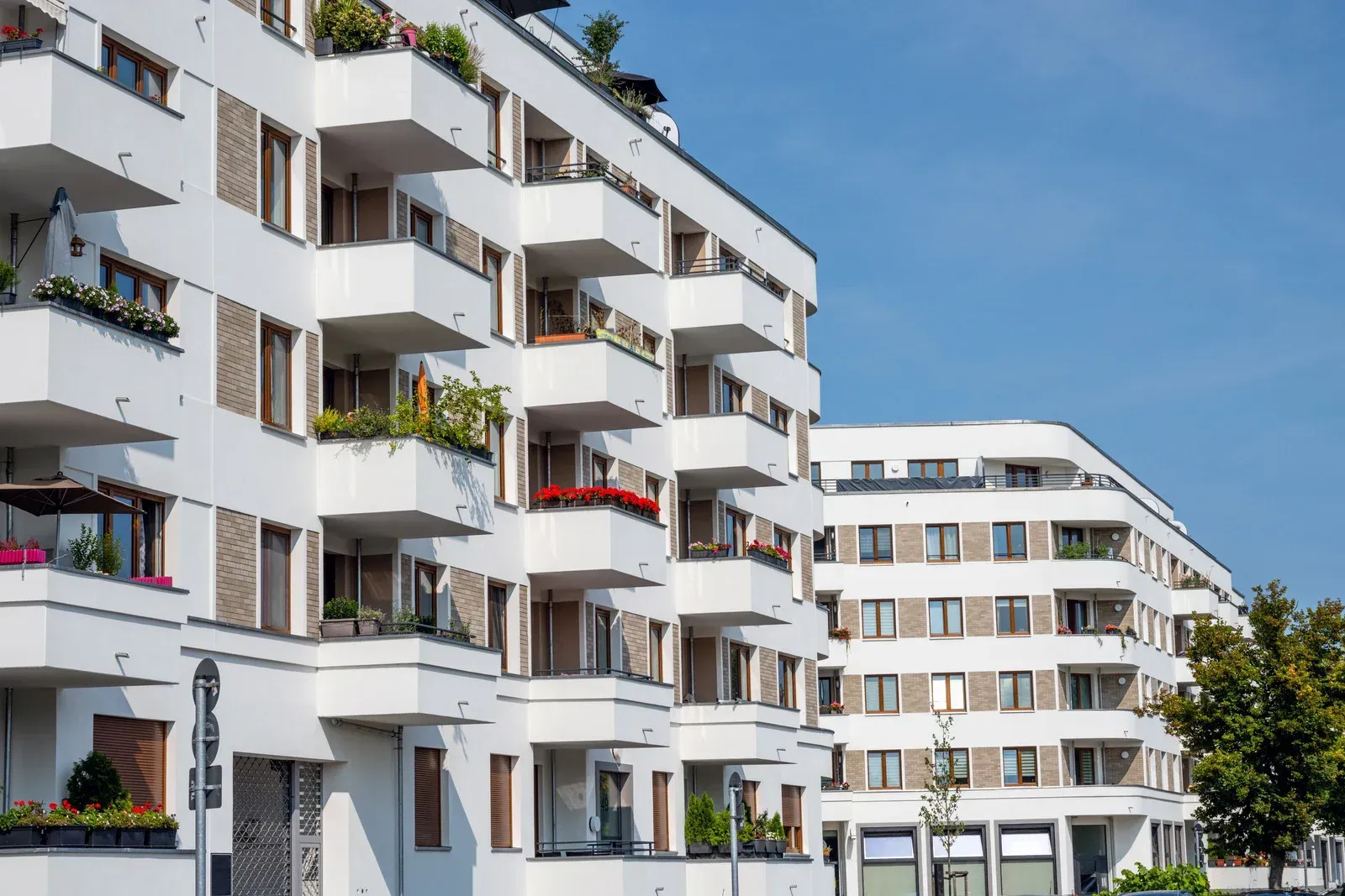 A row of apartment buildings with balconies and a blue sky in the background.