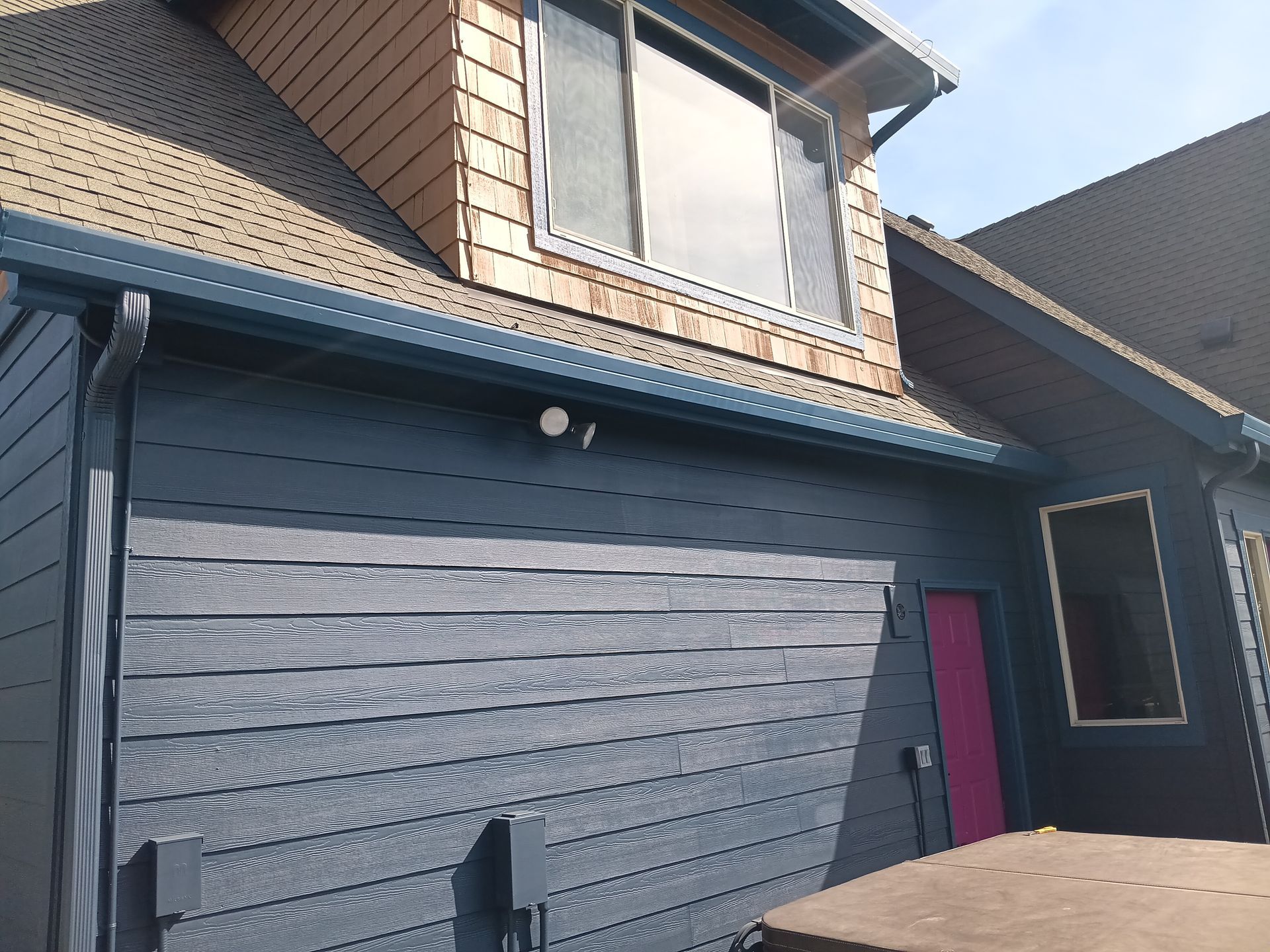 Modern dark-blue house exterior with garage, small window, and magenta front door