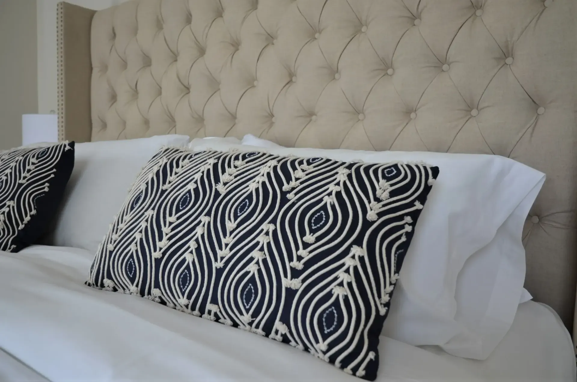 Un lit avec des draps blancs et des oreillers noirs et blancs