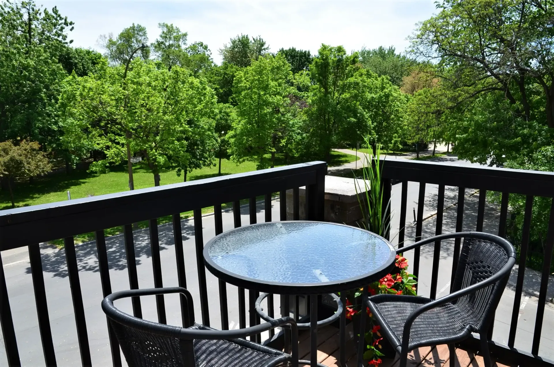 Un balcon avec une table et des chaises donnant sur un parc.