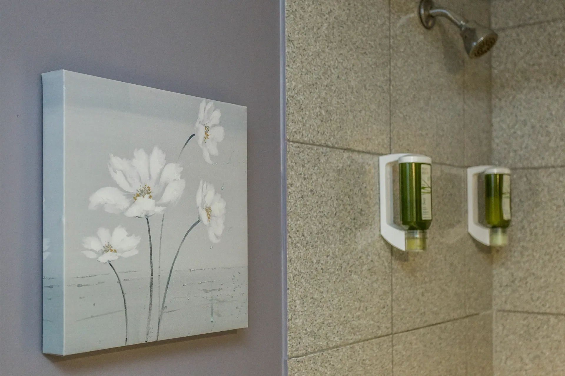 Un tableau de fleurs est accroché sur un mur à côté d'une douche.