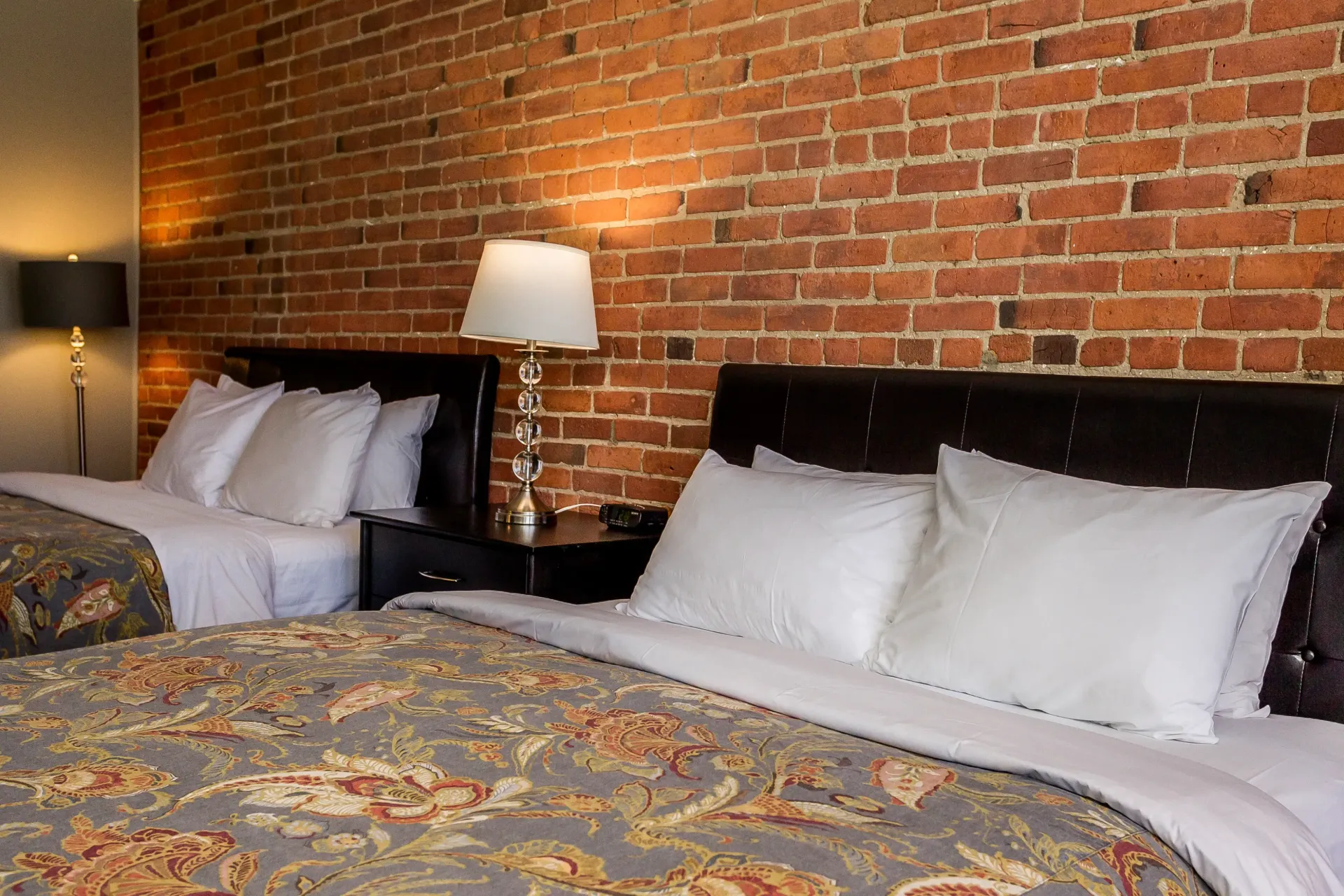 Une chambre d'hôtel avec deux lits et un mur de briques.