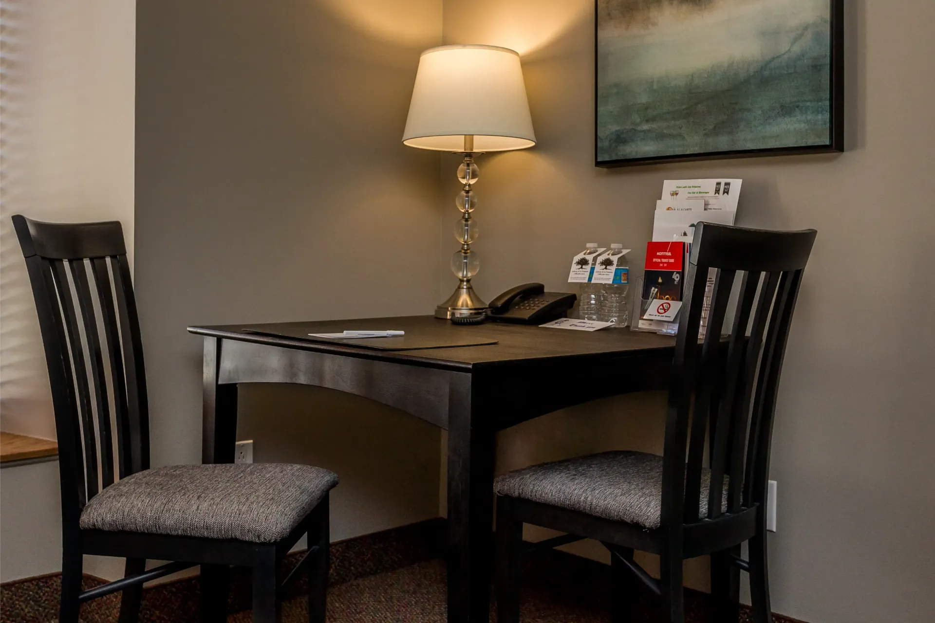 Un bureau avec deux chaises et une lampe dans une chambre d'hôtel