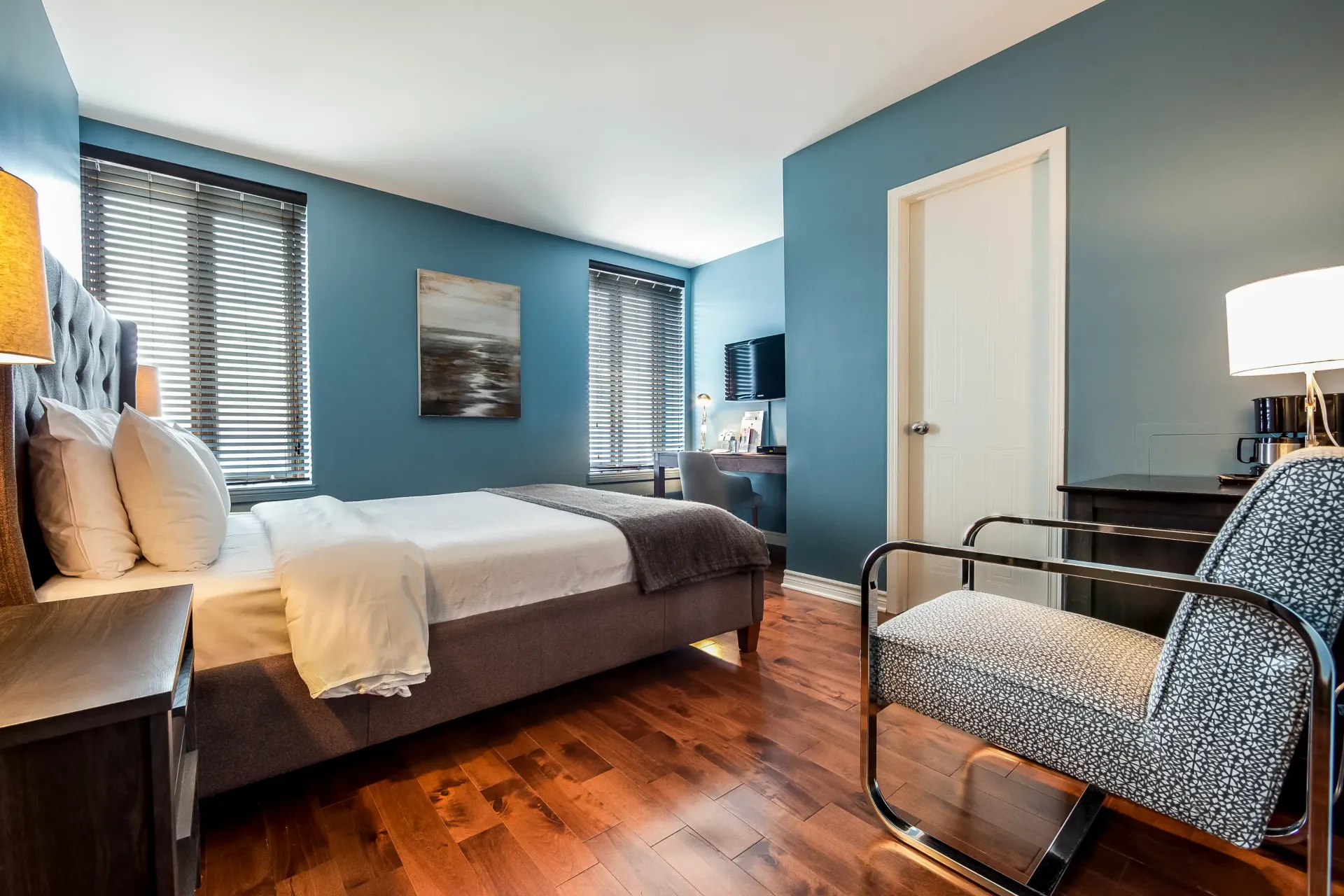 Une chambre avec un lit king size, une chaise, une table de chevet et des murs bleus.