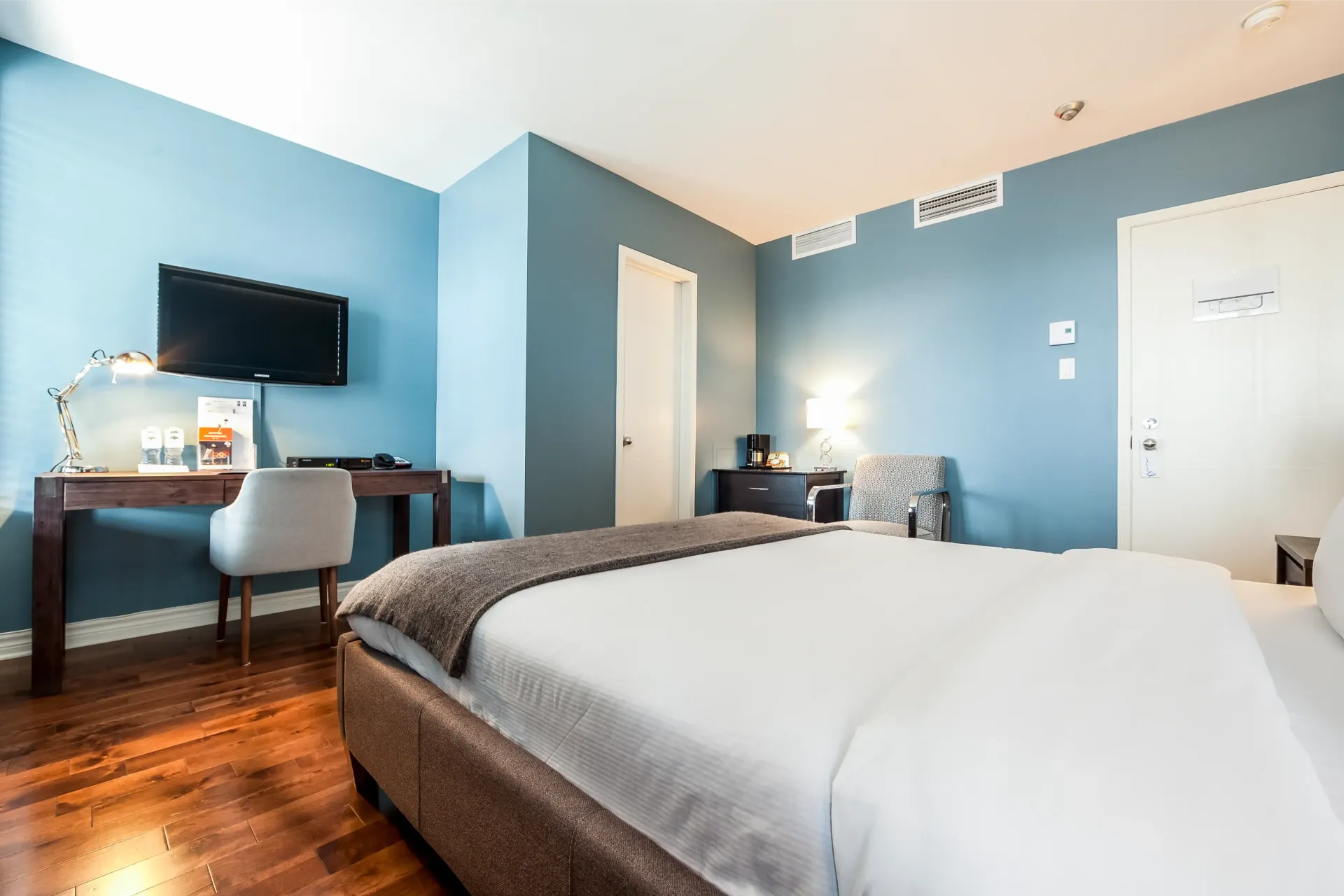 Une chambre d'hôtel avec un lit king size, un bureau, une chaise et une télévision.