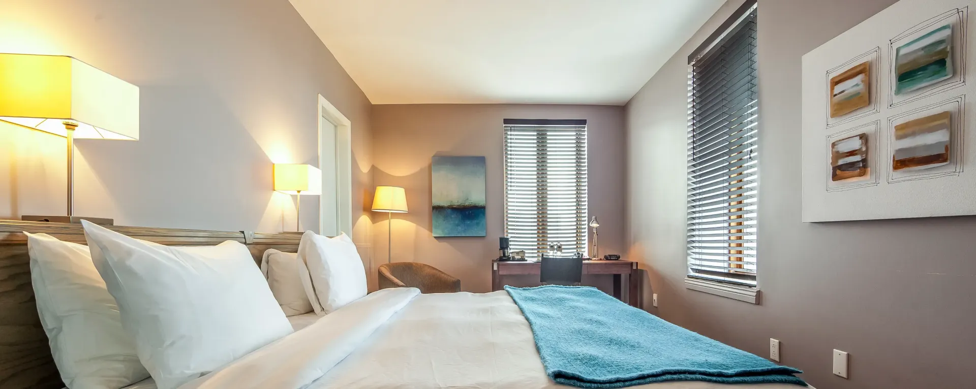 Une chambre avec un lit, des lampes et une fenêtre.