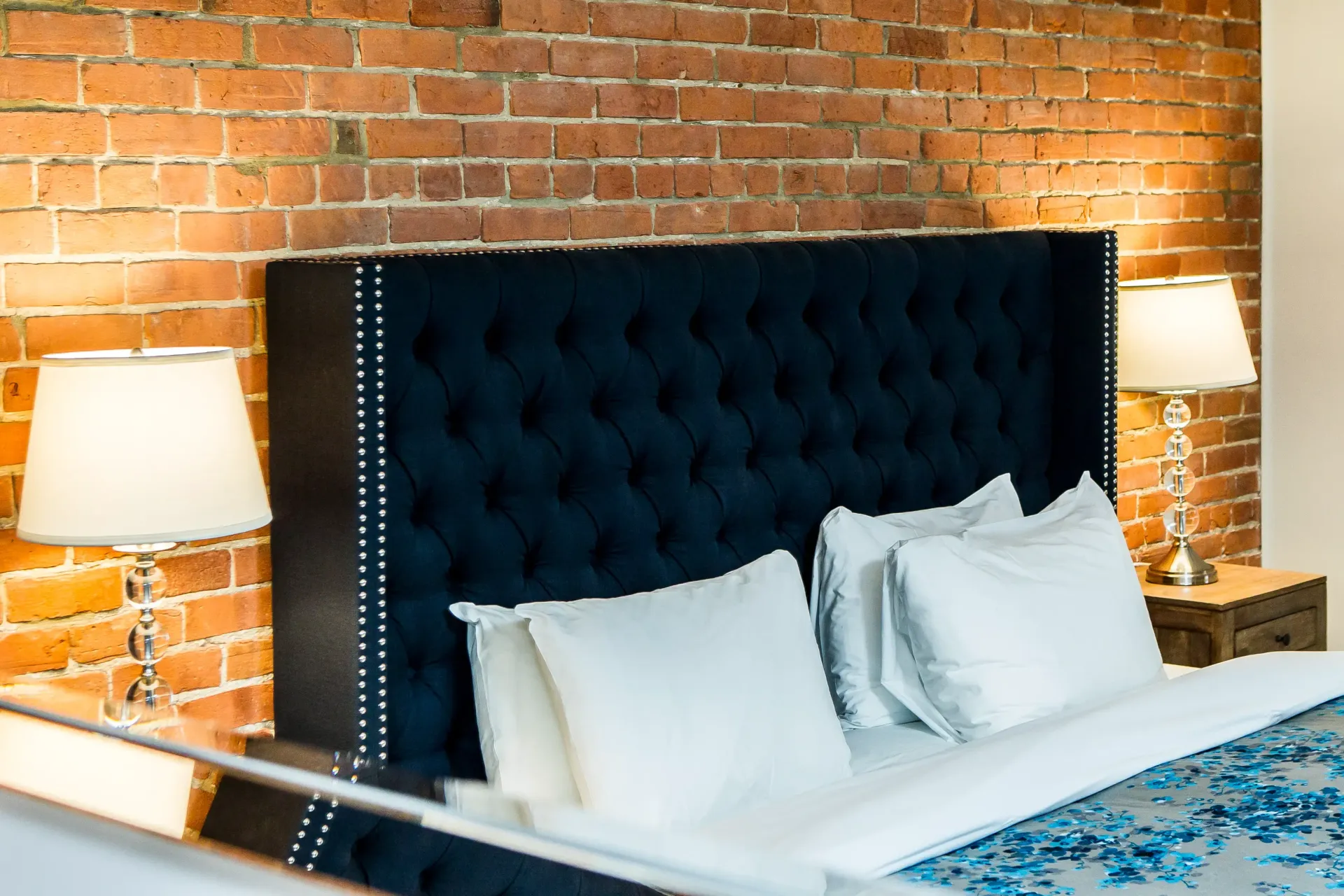 Une chambre d'hôtel avec un lit, des lampes et un mur de briques