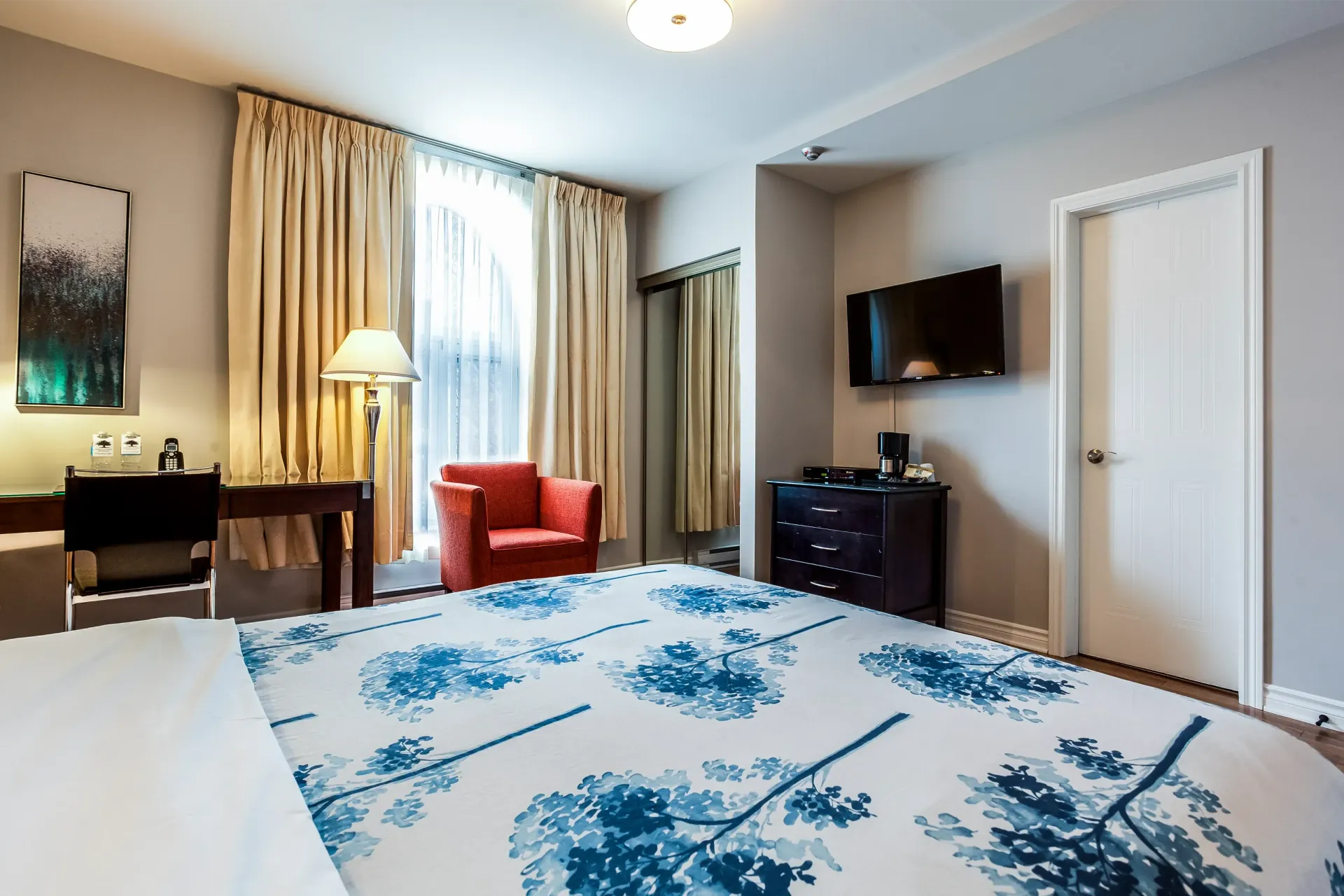Une chambre d'hôtel avec un grand lit, une chaise, un bureau et une télévision.