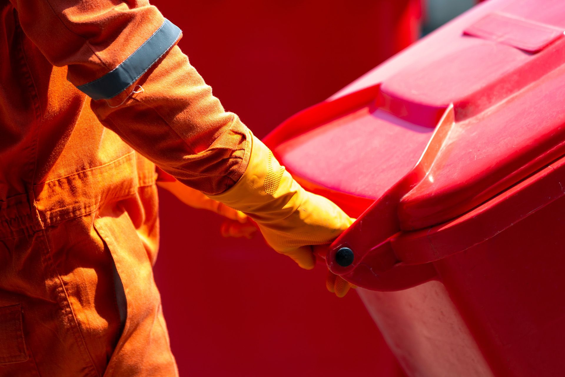 Worker pulling red bin wearing safety gear