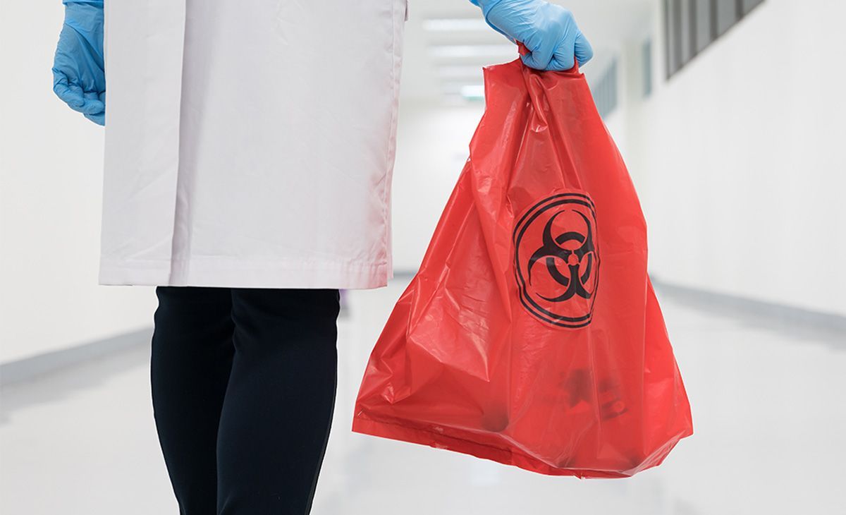 Medical staff carrying biohazard waste bag
