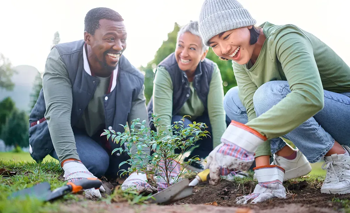 People smiling while planting a tree