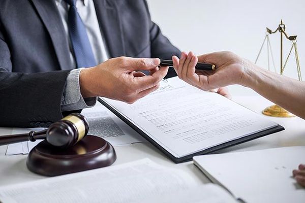 A man in a suit and tie is giving a pen to a woman.