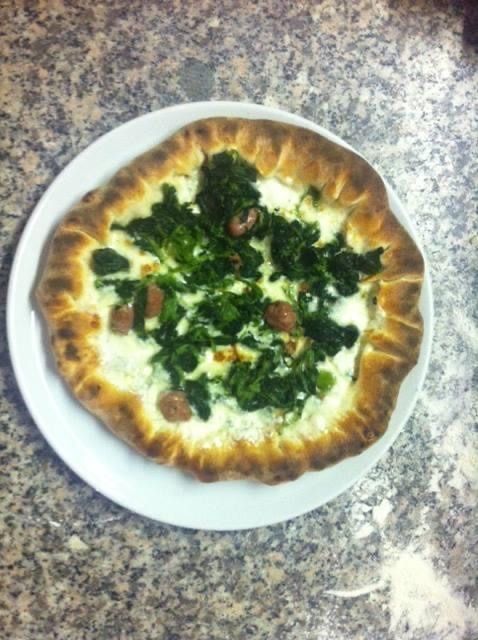 Torta salata su un piatto bianco; è caratterizzata da un ripieno bianco cremoso, guarnita con verdure verdi e piccoli pezzetti di salsiccia.