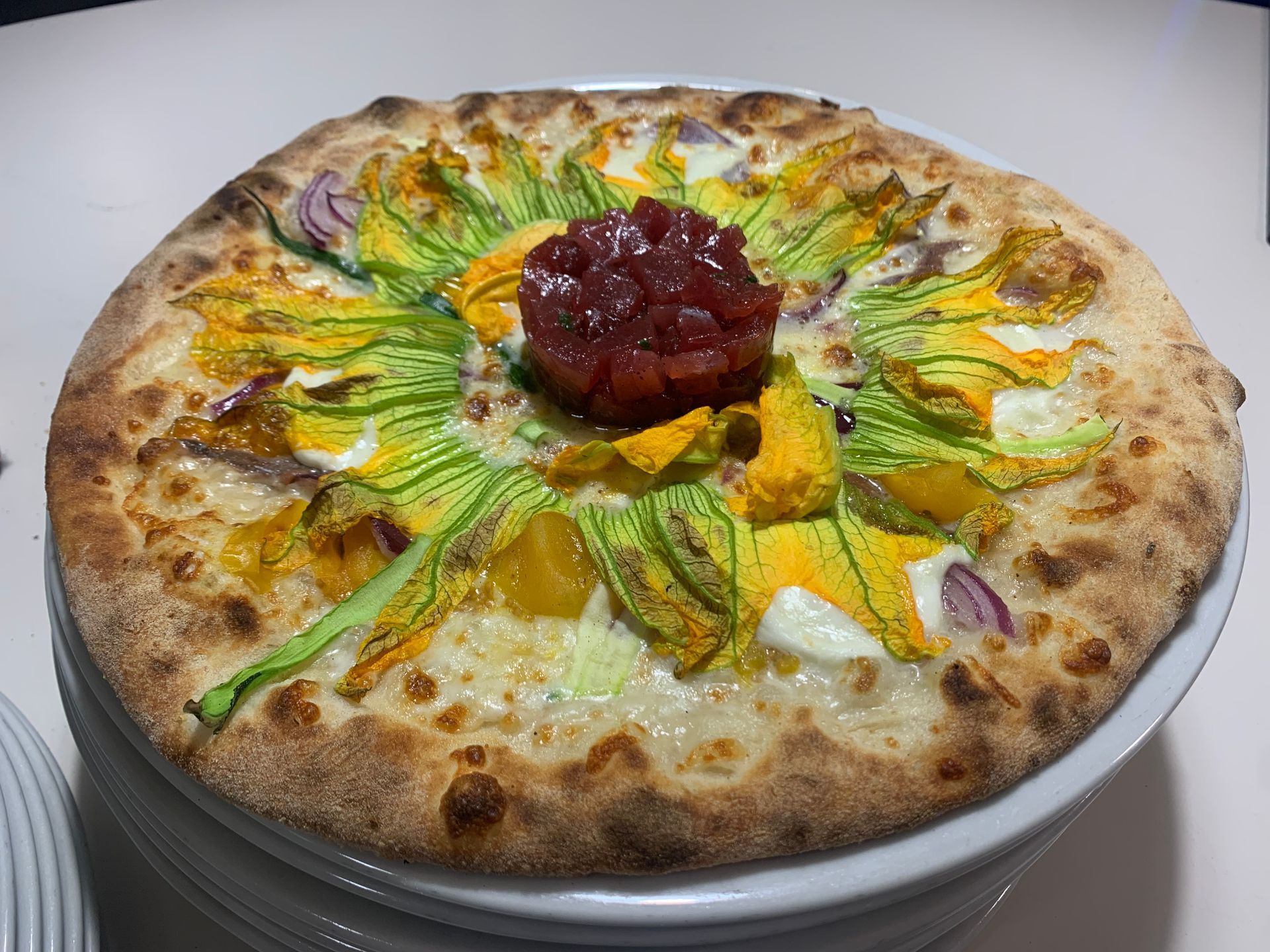 Pizza con prosciutto, fichi, noci e una pallina di formaggio bianco, servita su un tagliere di legno.