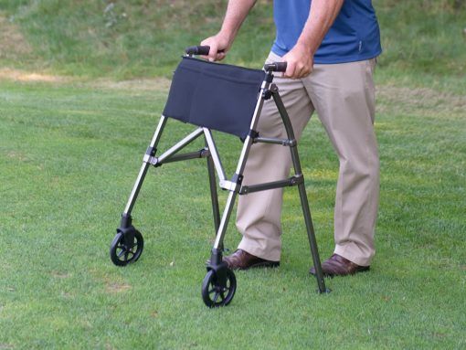 A man is using a walker on a lush green field.