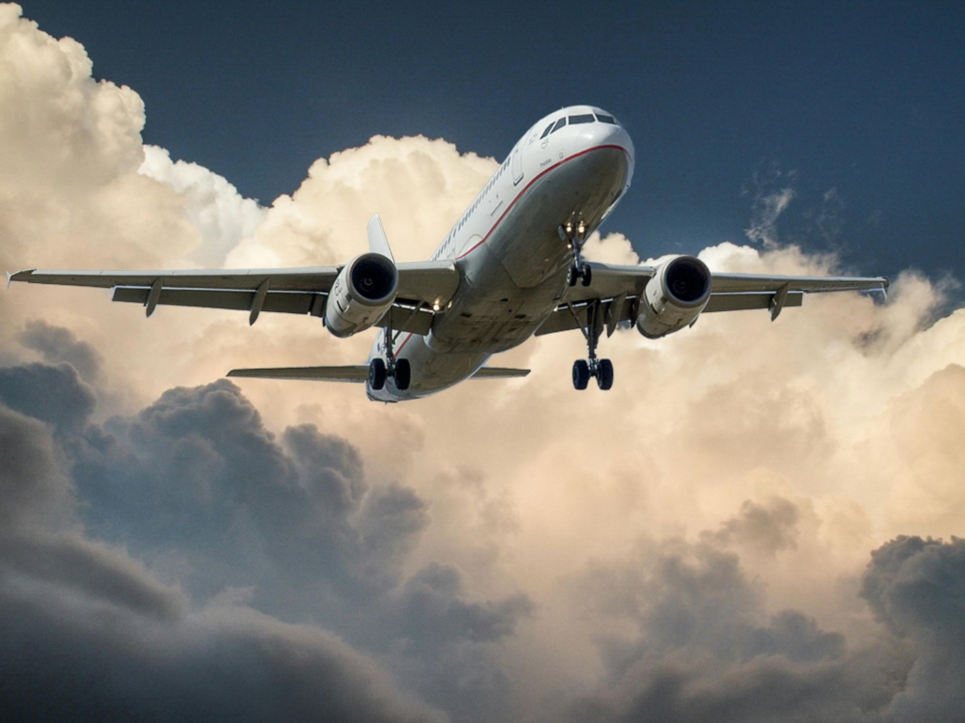 A large passenger jet is flying through a cloudy sky.