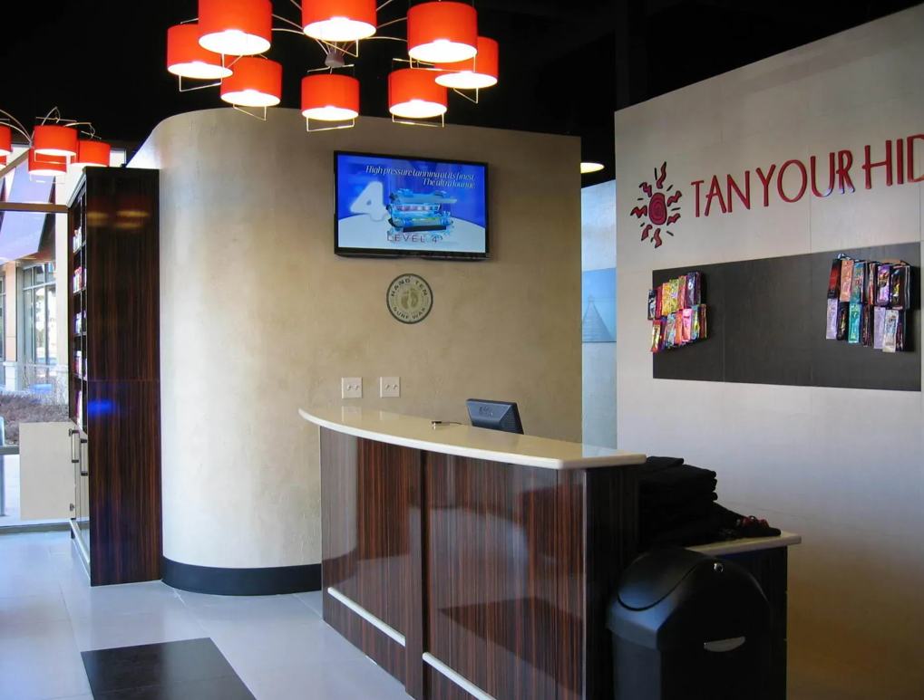 A salon reception area featuring a wooden front desk and a sign reading  