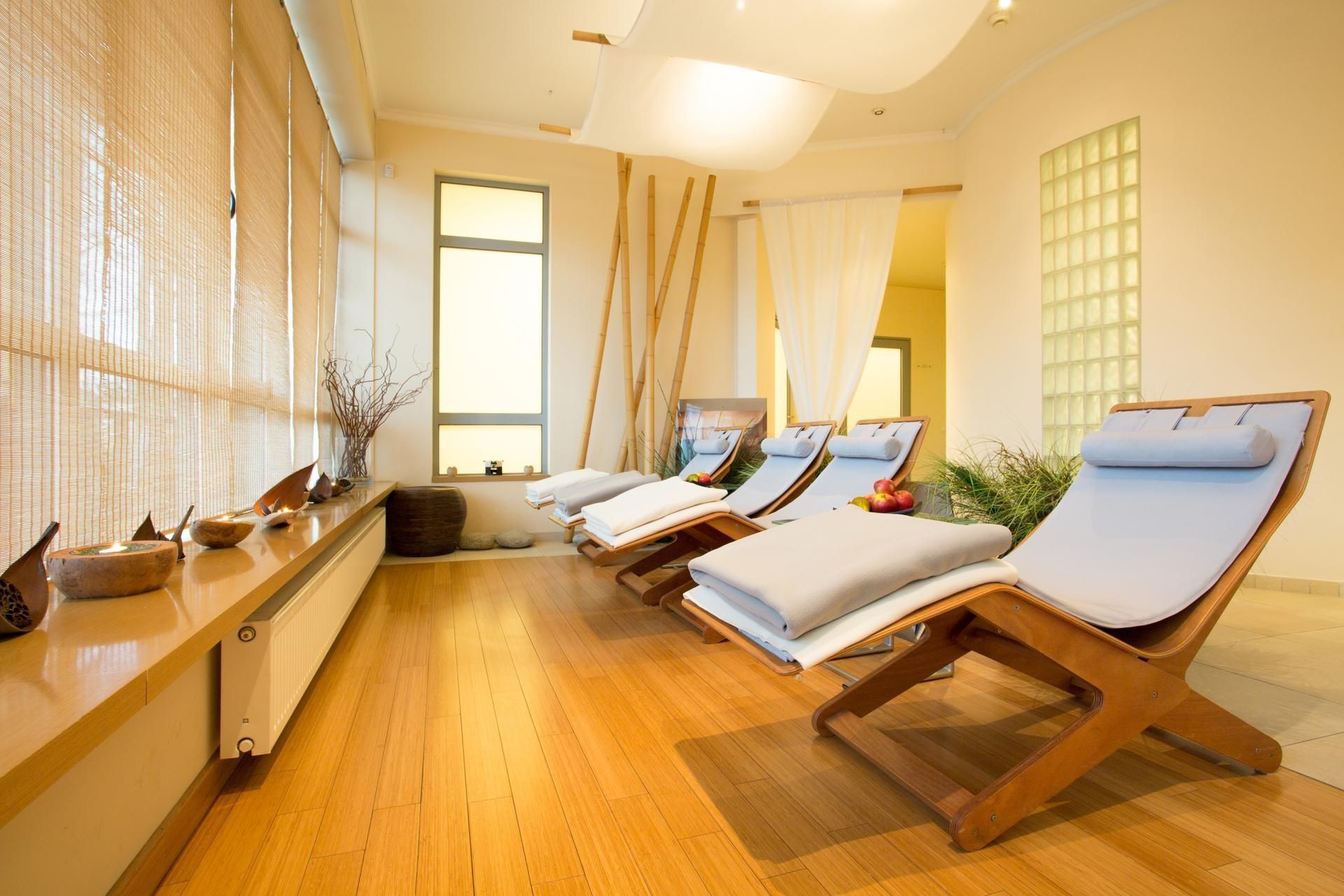 Relaxation room with wooden lounge chairs, bamboo shades, and natural light.