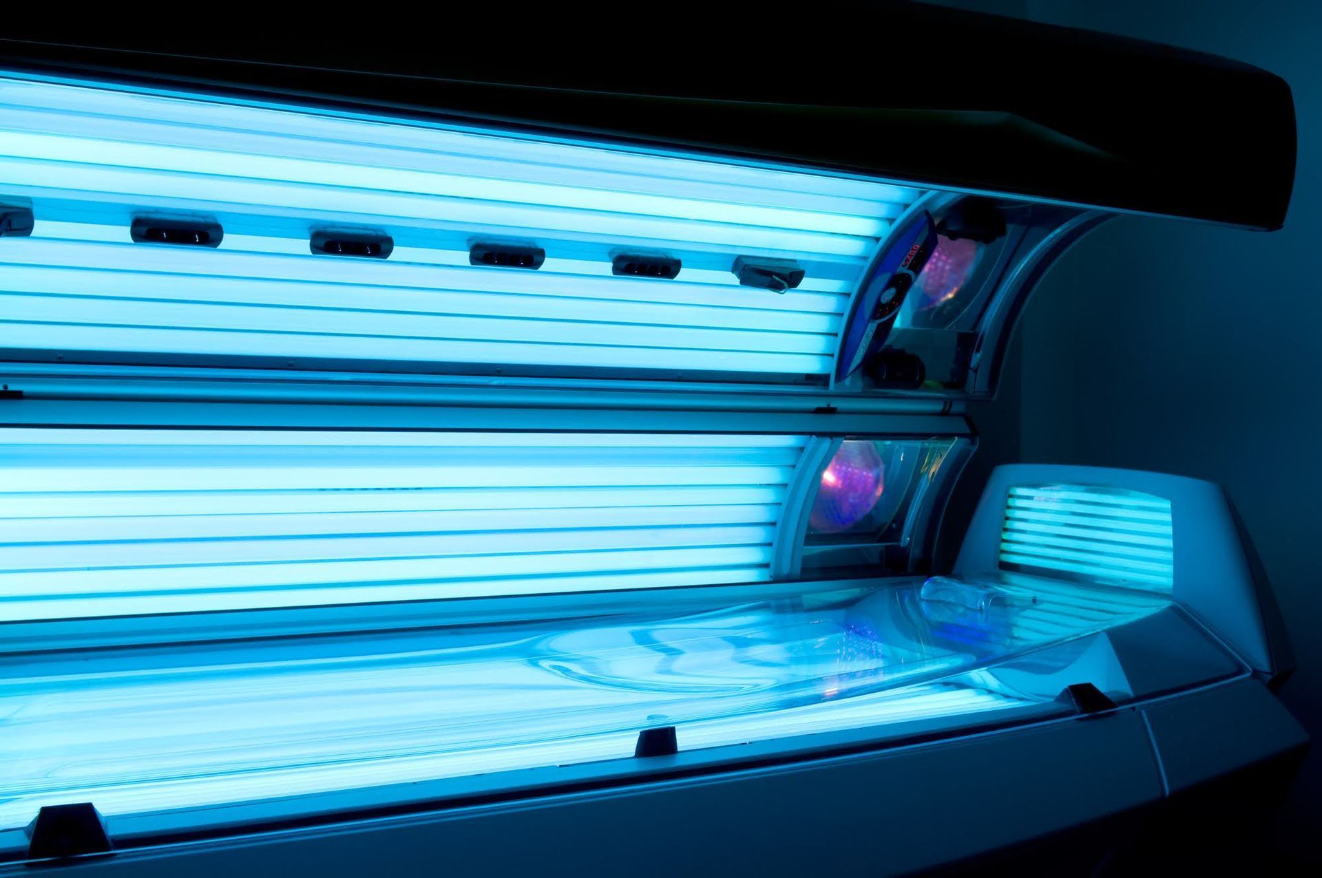 Tanning bed with bright blue UV lights; interior view.