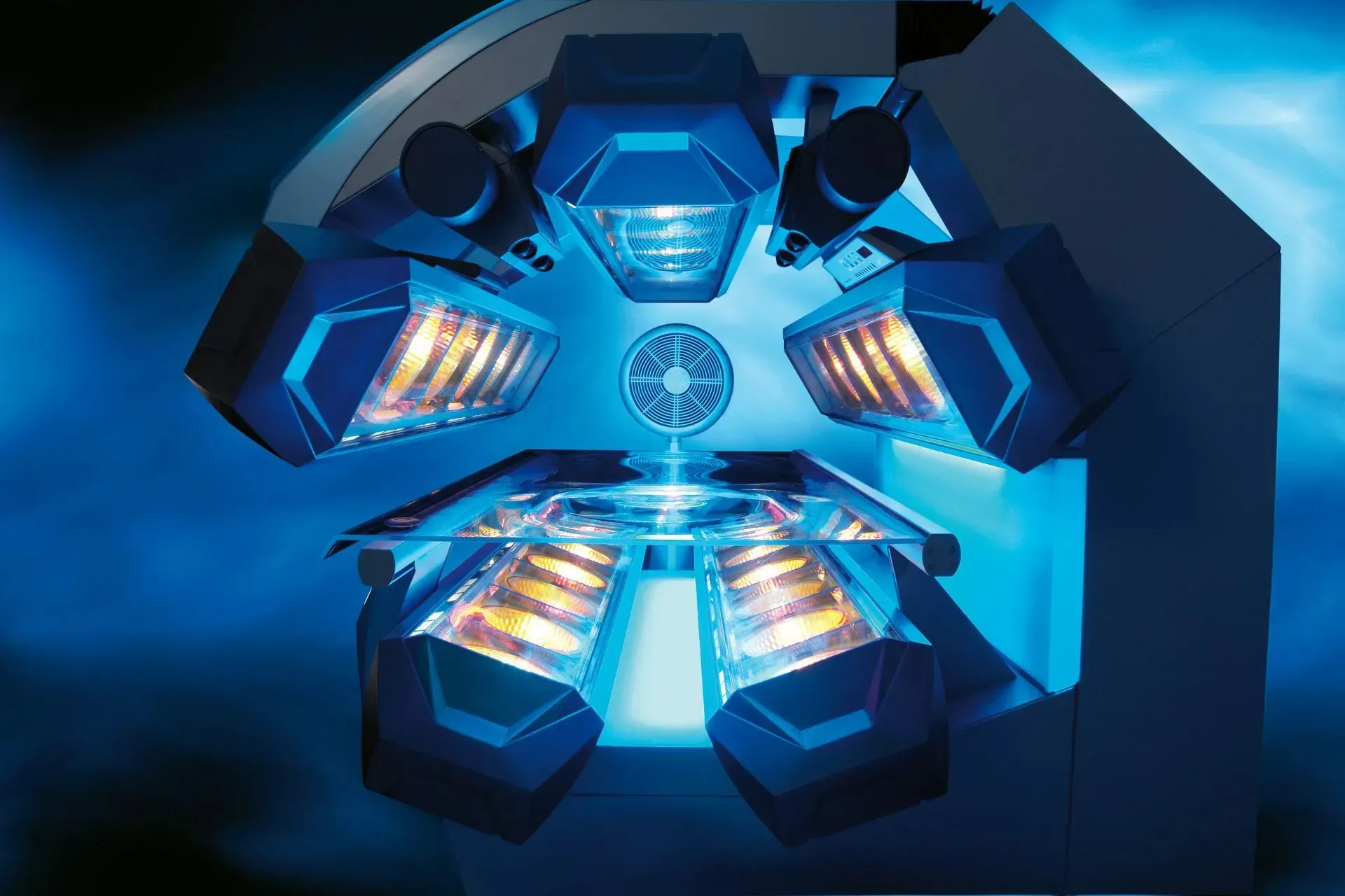 Blue and white tanning bed interior with six light panels surrounding a central platform.