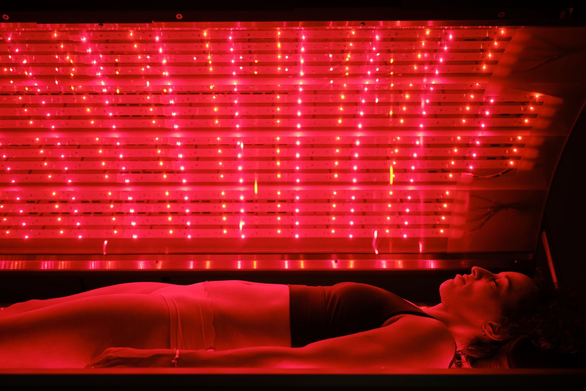 Woman lying in red light therapy bed.