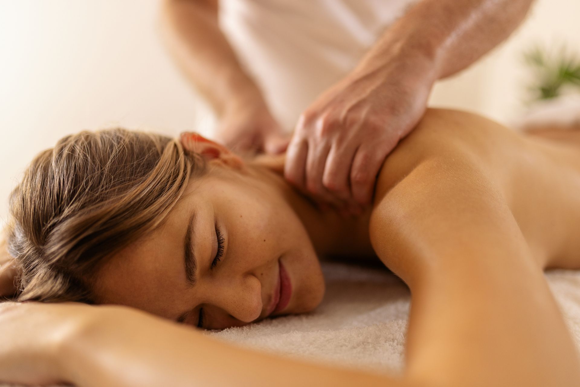 Woman receiving a shoulder massage, lying face down on a massage table.