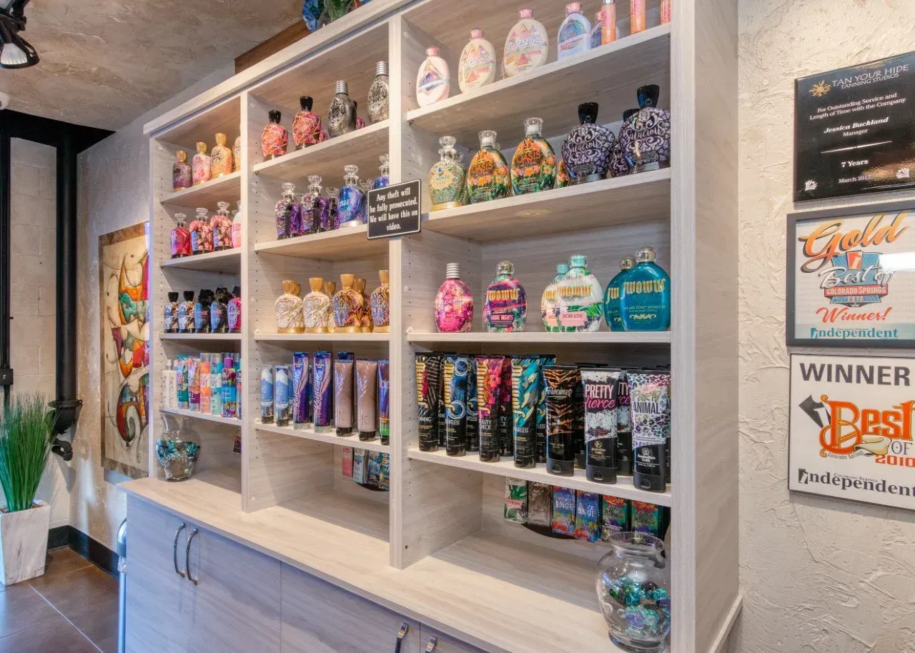 Shelves stocked with tanning lotions, creams, and awards in a store setting.