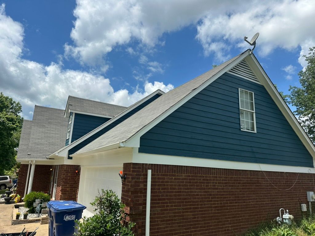 A brick house with a blue siding and a satellite dish on the roof.
