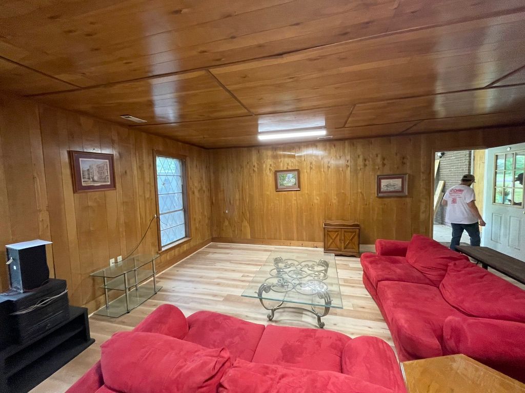A living room with red couches , a glass coffee table , and a wooden ceiling.