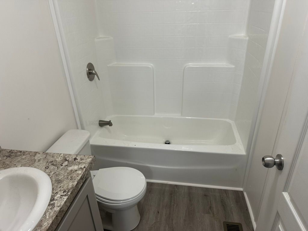 A bathroom with a toilet , sink and bathtub.