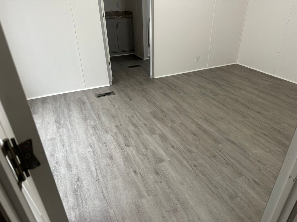 A room with a gray wooden floor and white walls.