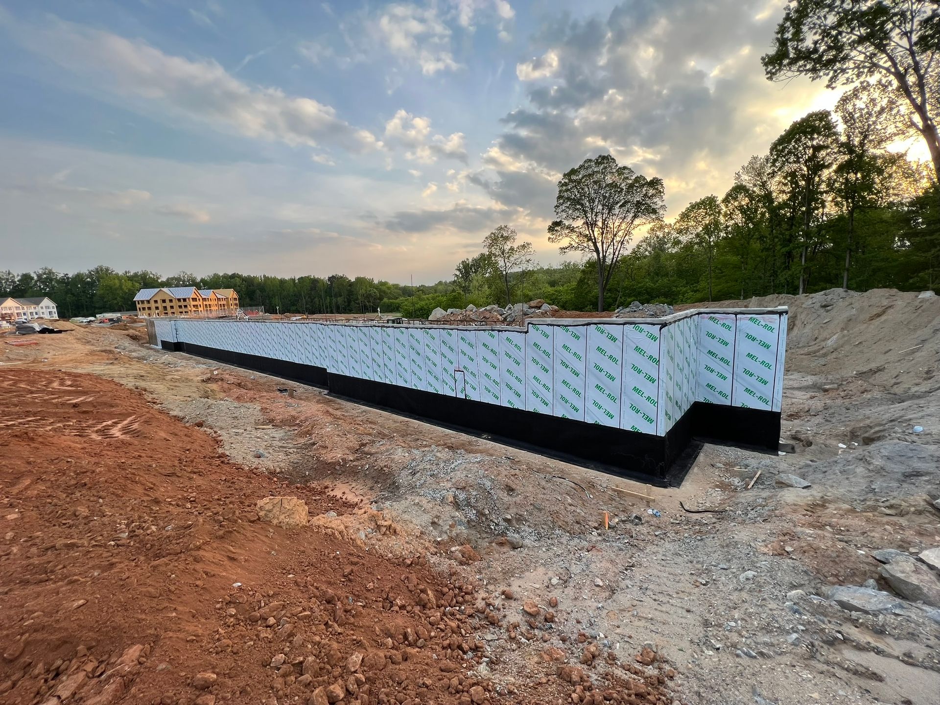 A large concrete wall is being built in a dirt field.
