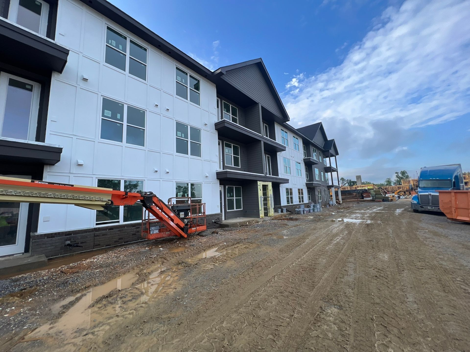 A large apartment building is being built next to a dirt road.