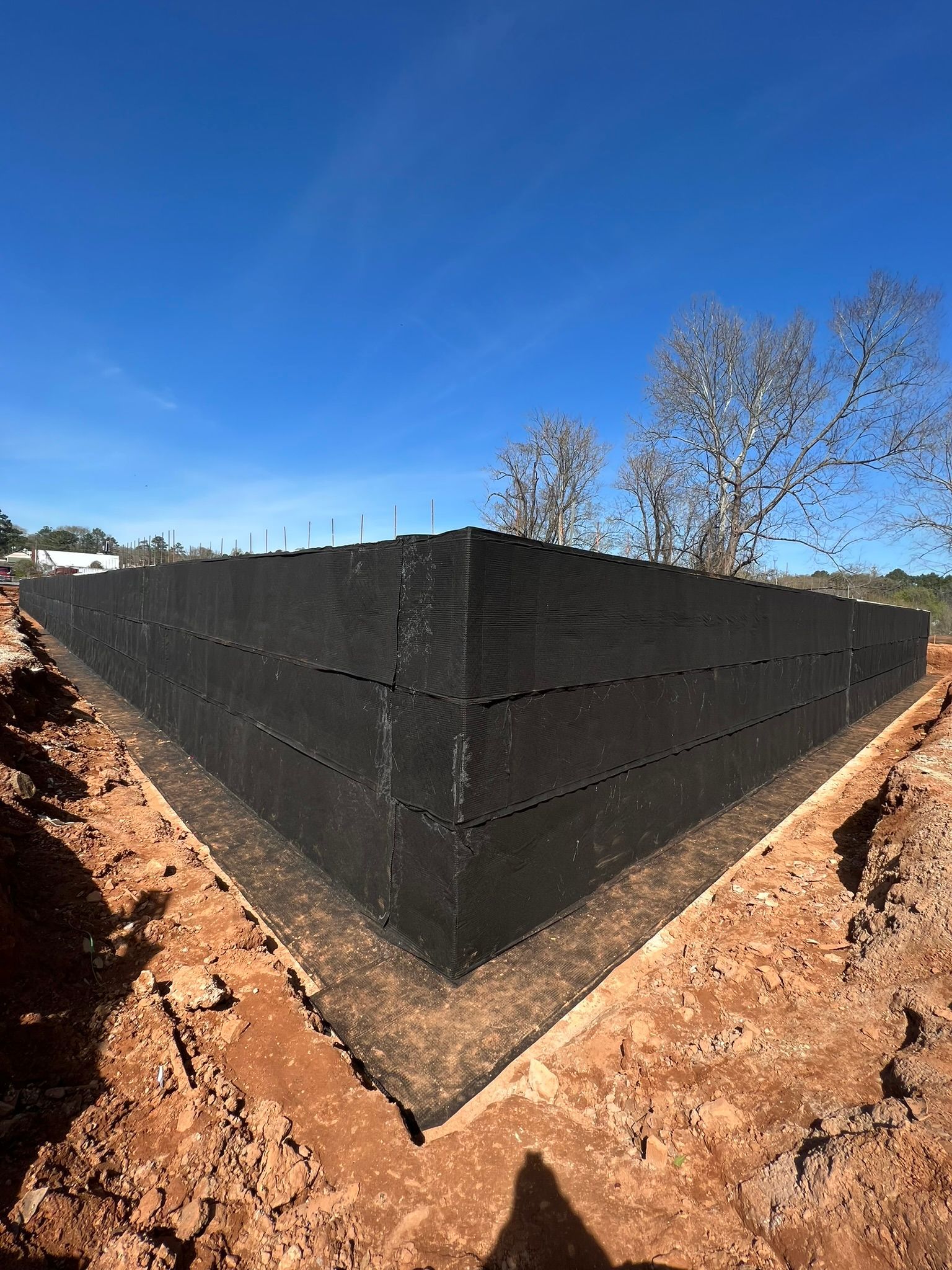 A large black wall is sitting in the middle of a dirt field.